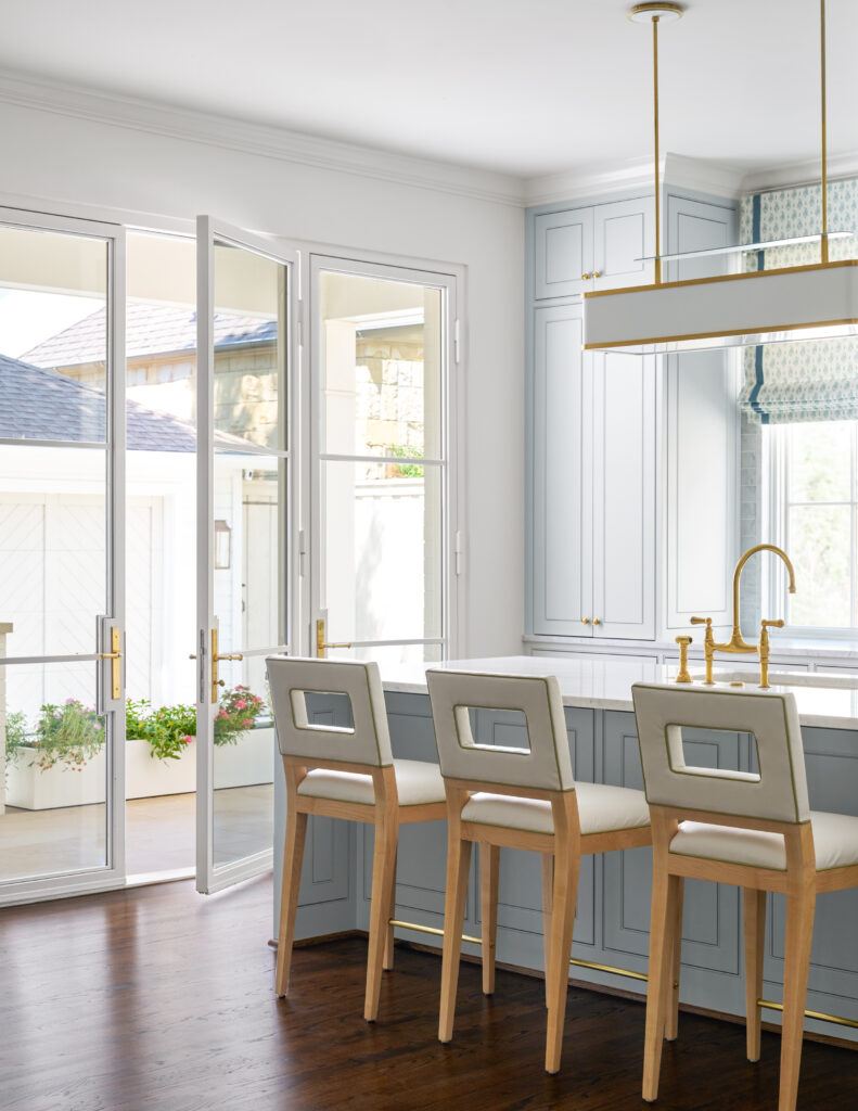 Luxury pale blue kitchen custom made with large glass window doors, gold sink, and modern blue cabinets made by Gillis custom homes in dallas texas