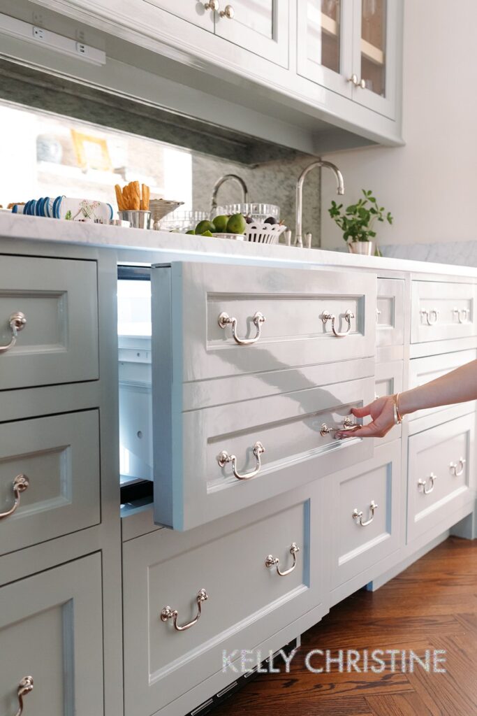 Recent project of a luxury custom home with a client chosen hand crafted cabinets, light blue painted trim over a beautiful bar with a built in drawer fridge or refrigerated drink drawer built by Gillis Custom Homes in Dallas Texas